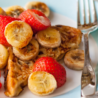 Toasted bread on a plate topped with slices of banana and strawberries.