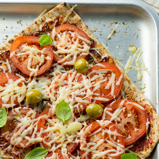 Square pizza, topped with tomatoes, basil, olives and melted cheese.